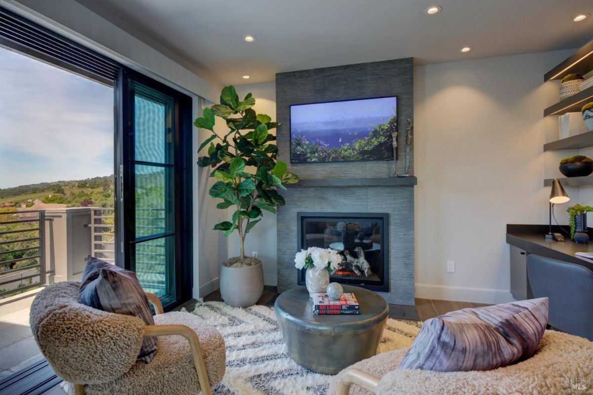 Seating area with a modern fireplace, a TV, and a balcony view through sliding glass doors.