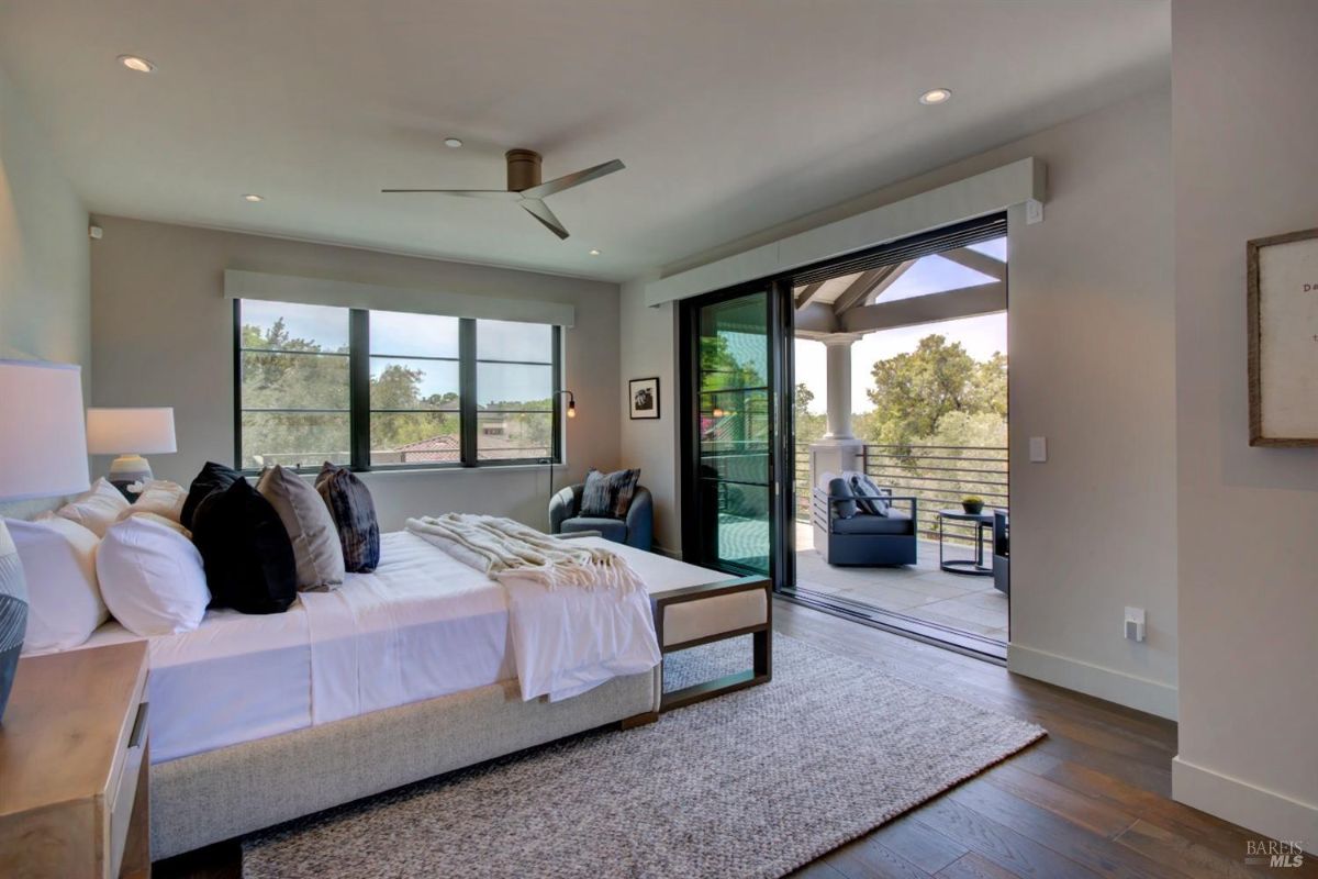 Bedroom with a large bed, multiple windows, and access to a private balcony through sliding doors