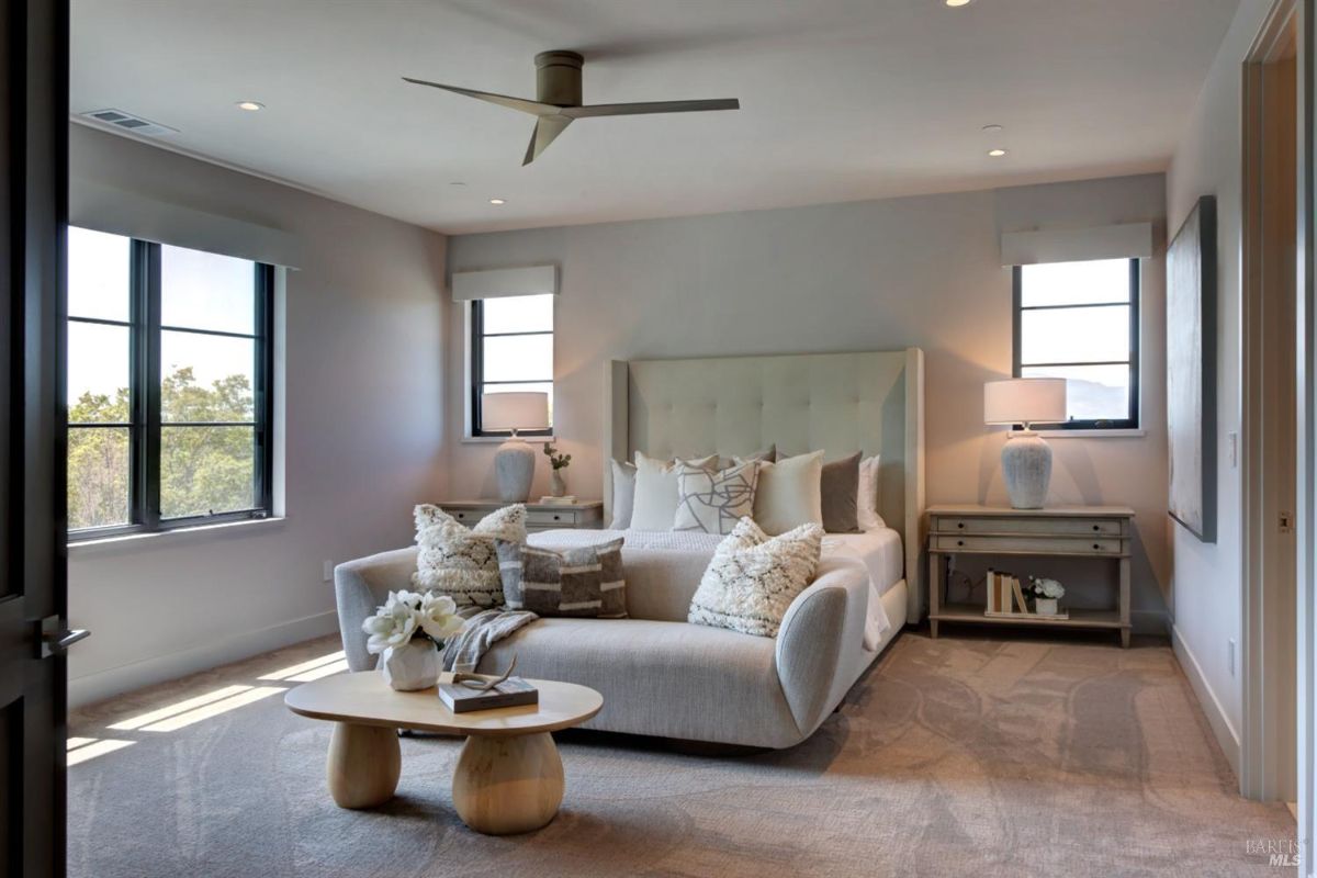 Bedroom with a large upholstered bed, a bench, and windows providing ample natural light.