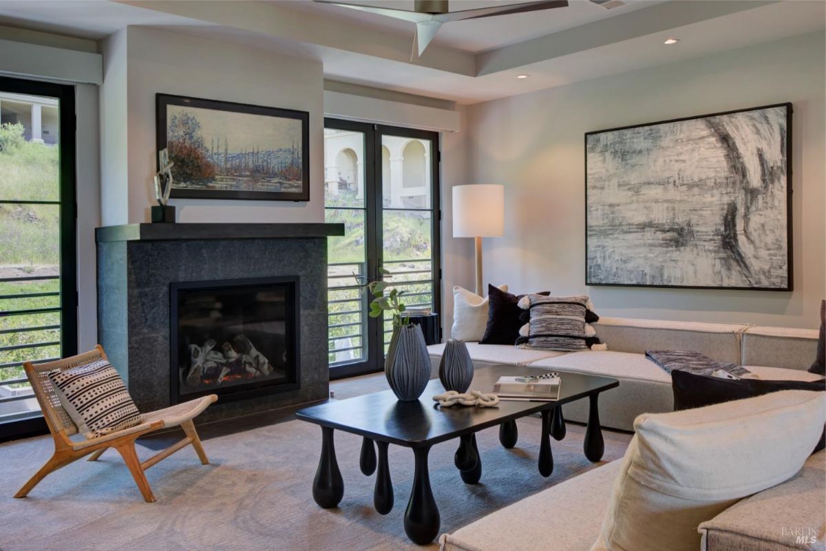 Sitting room with a fireplace, large sectional sofa, and abstract art pieces on the walls.