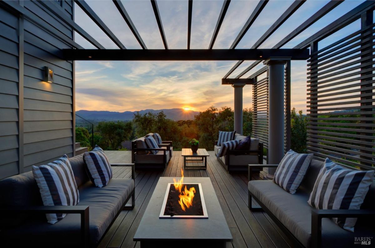 Patio with fire pit and striped cushions offering views of the sunset.