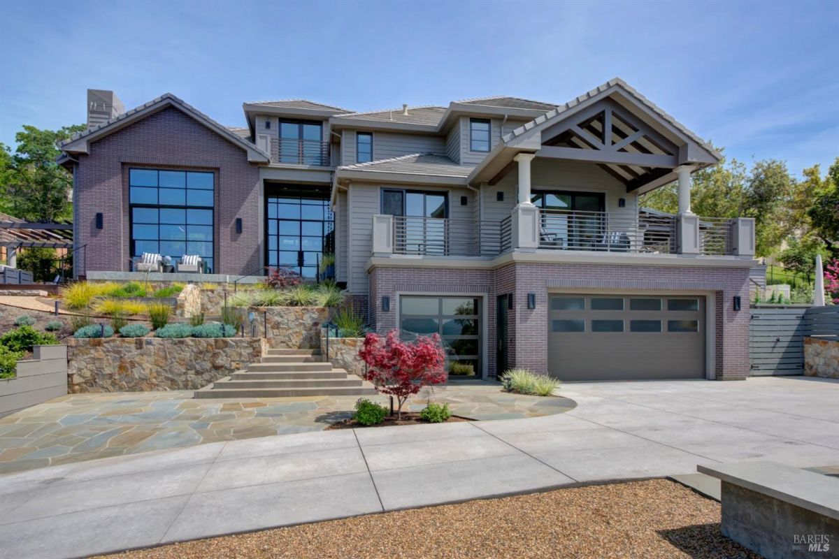 A daytime front view of the home with a stone walkway, modern garage doors, and landscaped garden.