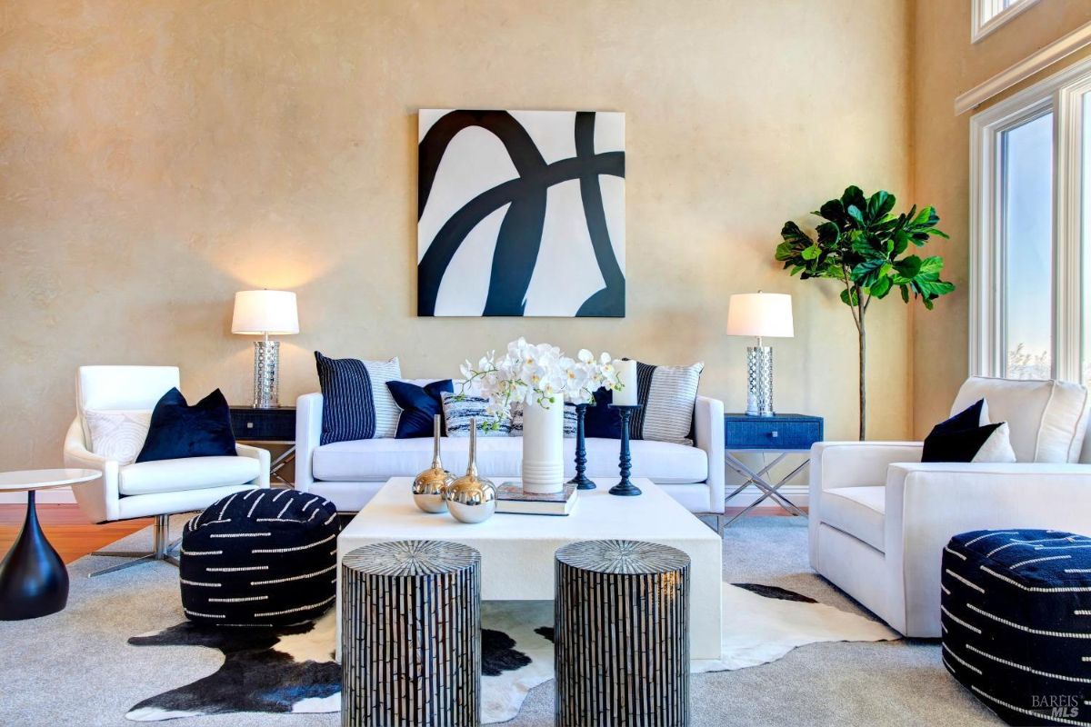 Modern living room with white furniture, a central table, and large abstract artwork.