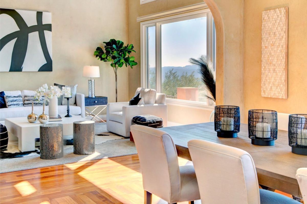 Dining area adjacent to the living room, showcasing a wooden table and chairs with a large window overlooking the landscape.