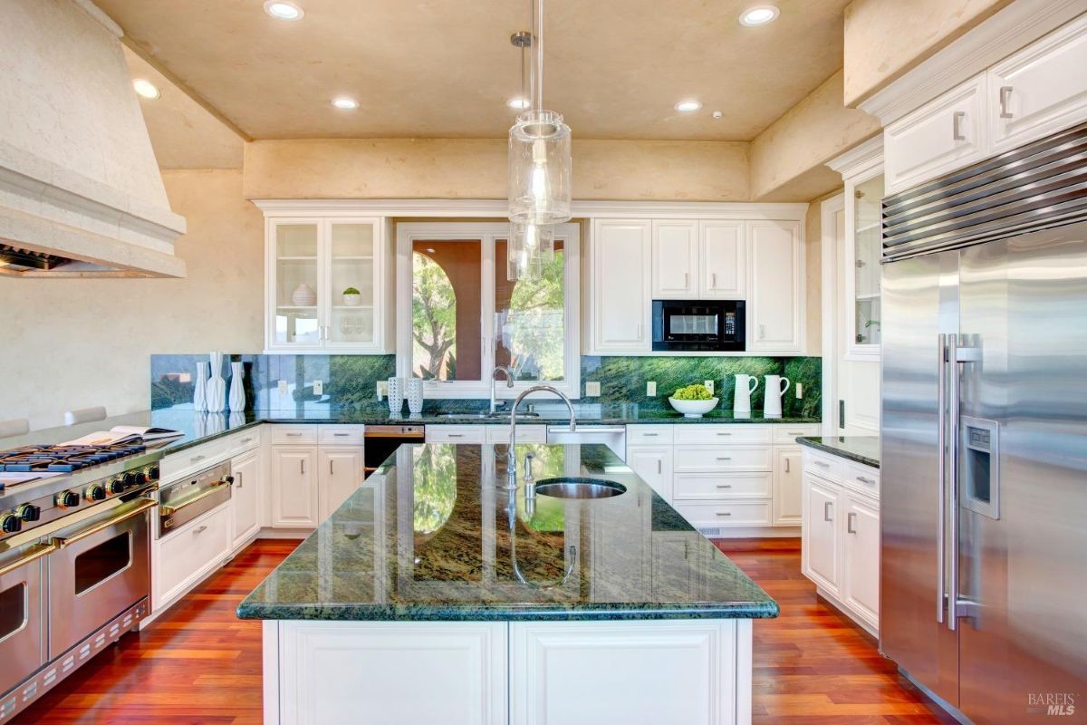 Kitchen featuring stainless steel appliances, white cabinetry, and an island with pendant lighting.