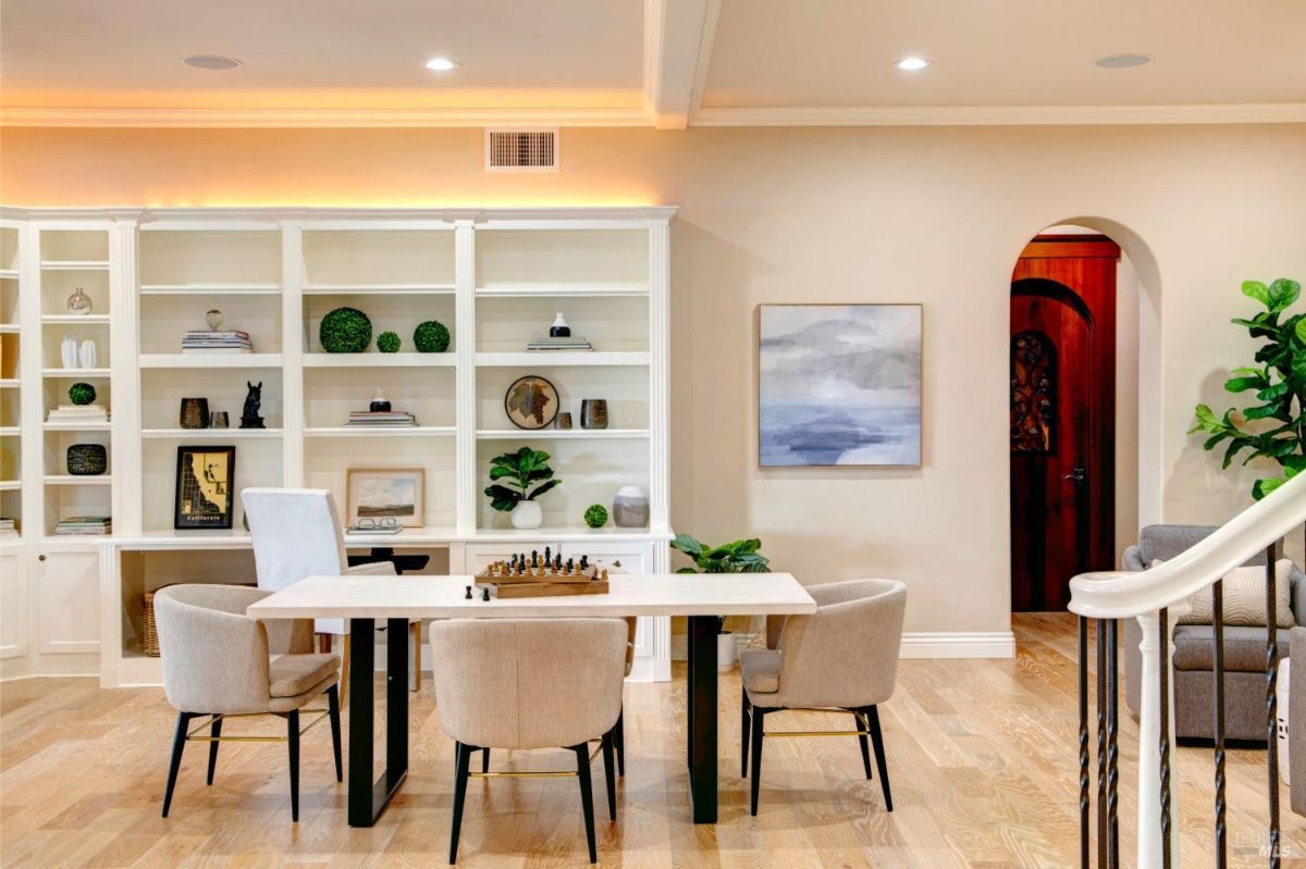 Seating area in the recreational space featuring bookshelves and a door with an arched design in the background.