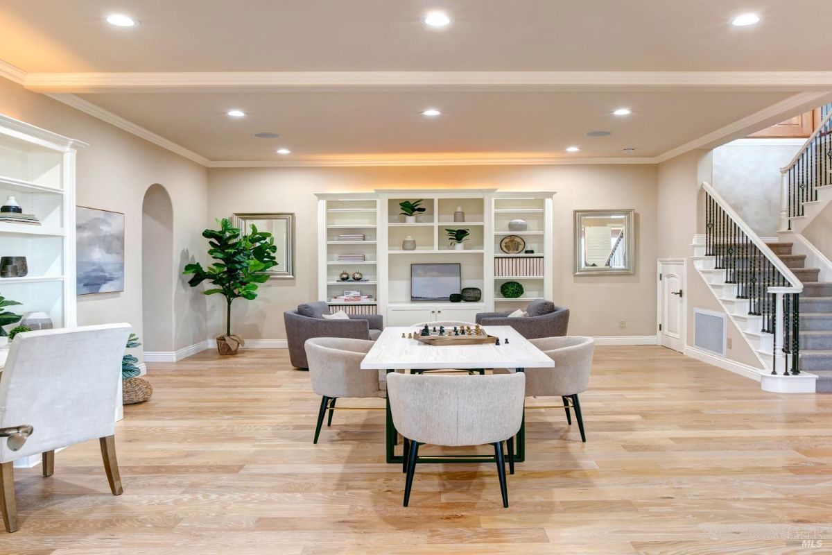 Open recreational space with bookshelves, a table for chess, and a staircase leading to another level.