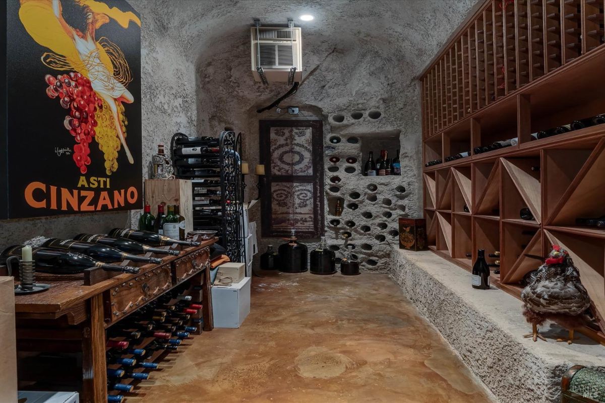 Wine cellar with stone walls, wooden racks, and a colorful poster.