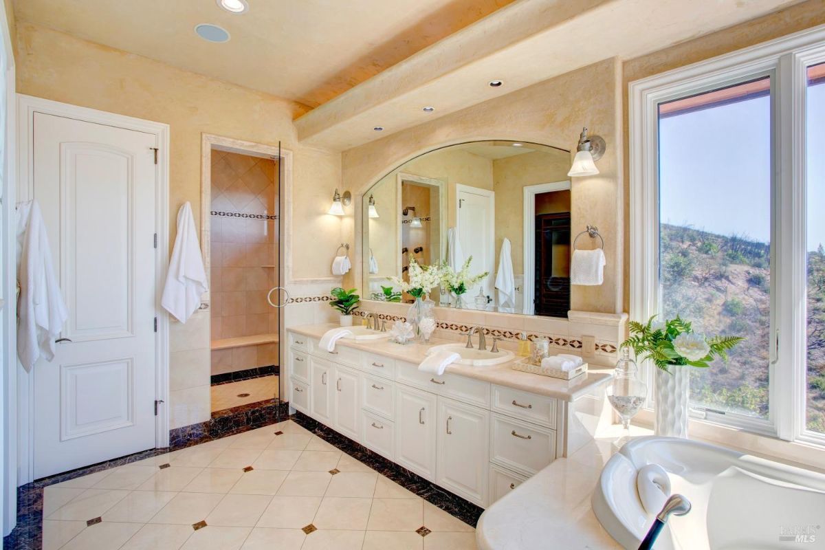 Bathroom has a double sink vanity, a large mirror, and a walk-in shower.