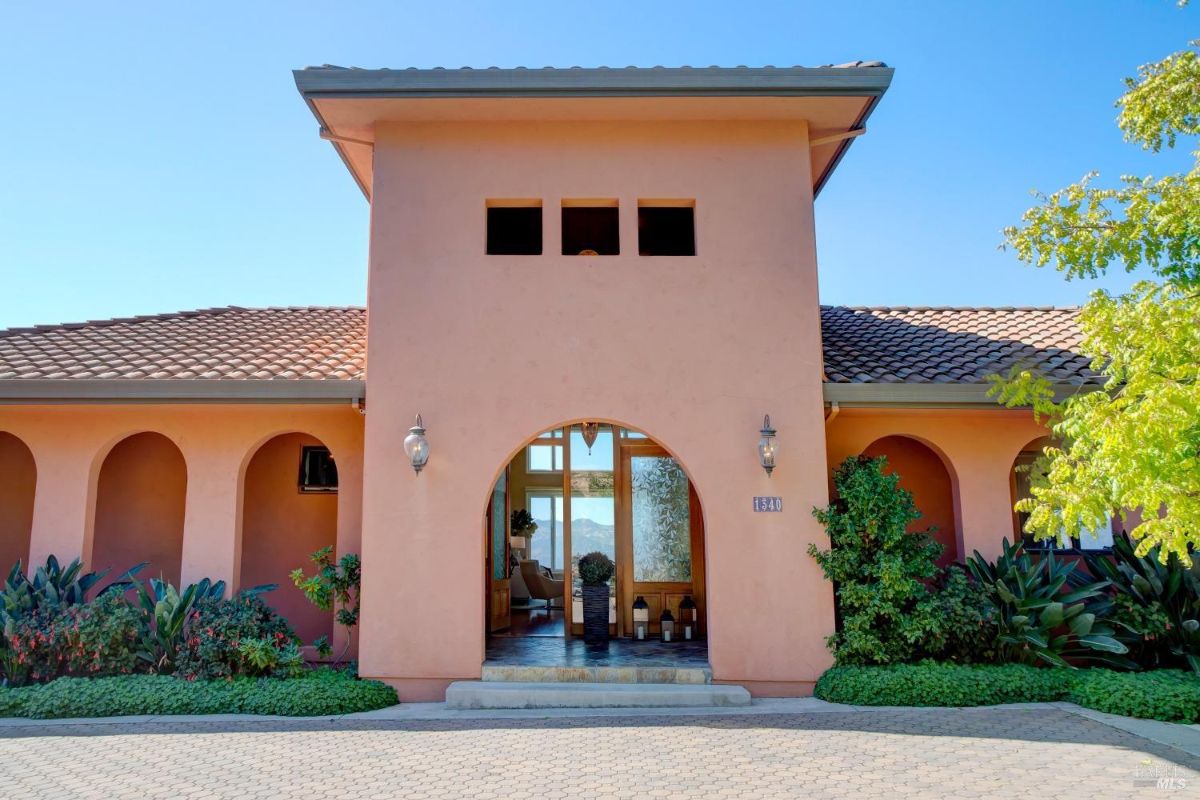 Close-up of the front entrance with an arched doorway and decorative landscaping.