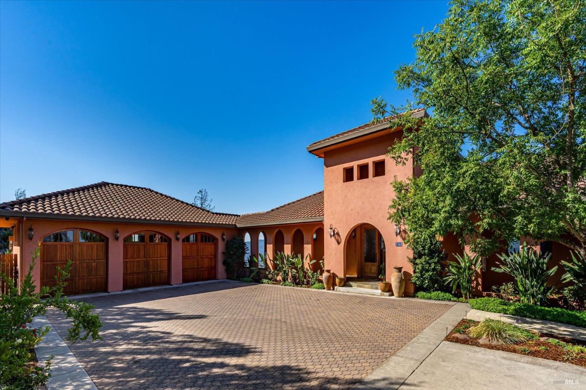 Front exterior with a paved driveway, a three-car garage, and terracotta roofing.