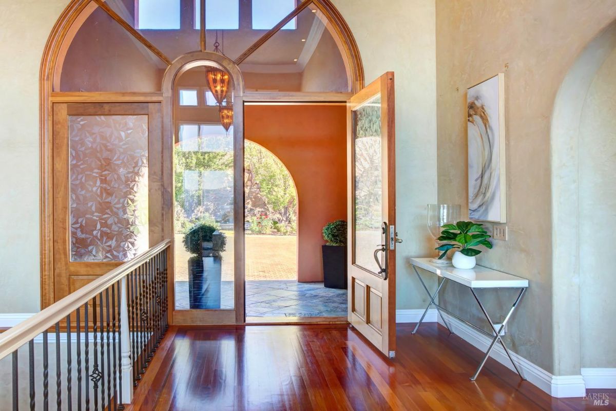 Entryway with glass doors, a view of the front yard, and polished wooden flooring.