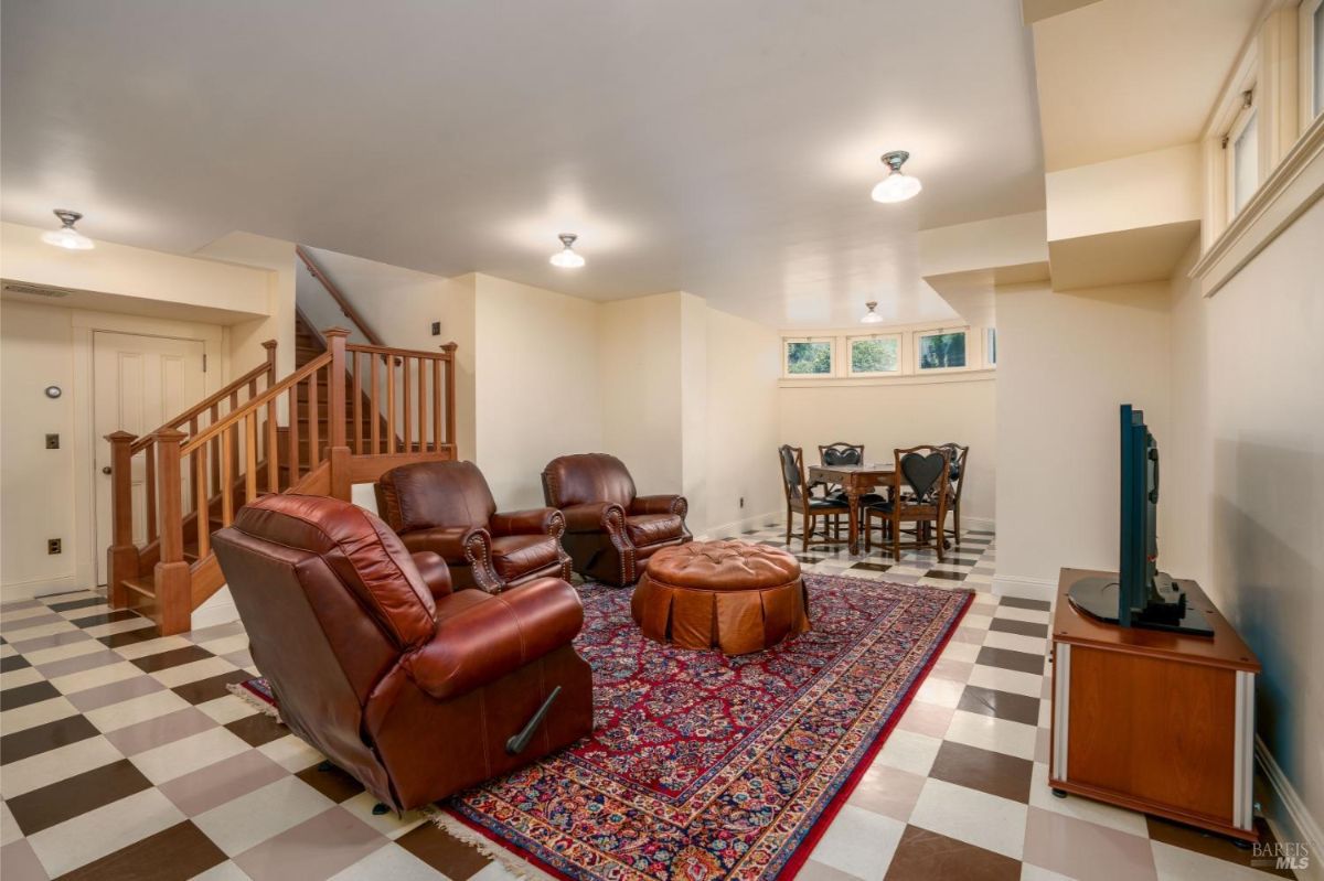 : A basement living area featuring checkered flooring, comfortable leather seating, and a small dining area. The space is cozy and well-lit with natural and overhead light.