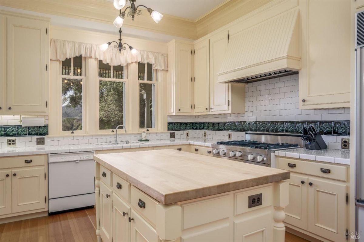 A closer look at the same kitchen, emphasizing the high-end gas range, tiled backsplash, and ample cabinetry. The craftsmanship highlights classic, high-quality design.