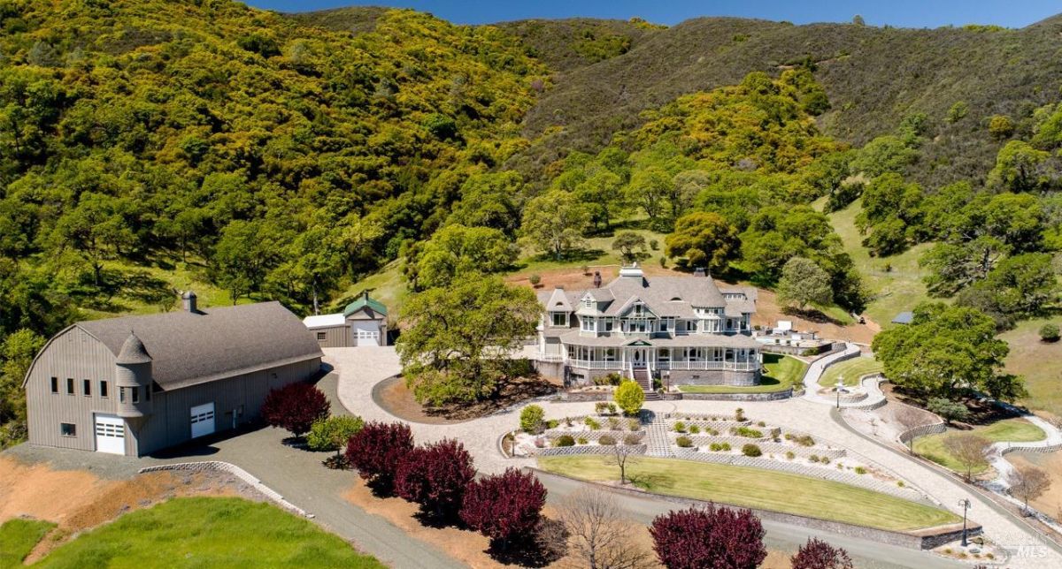 Estate view showcasing a grand house surrounded by lush greenery and hills.