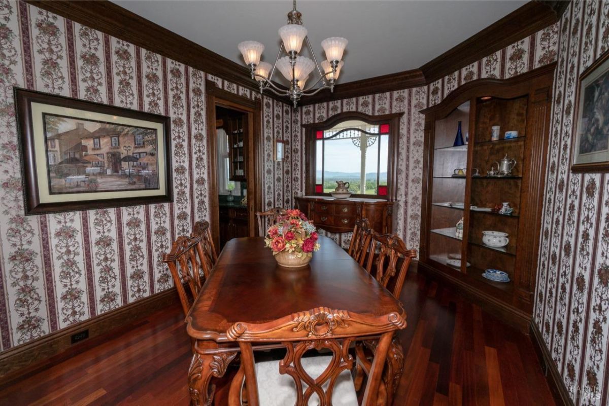 Classic dining area with large windows showcasing scenic views and intricate wooden furnishings.