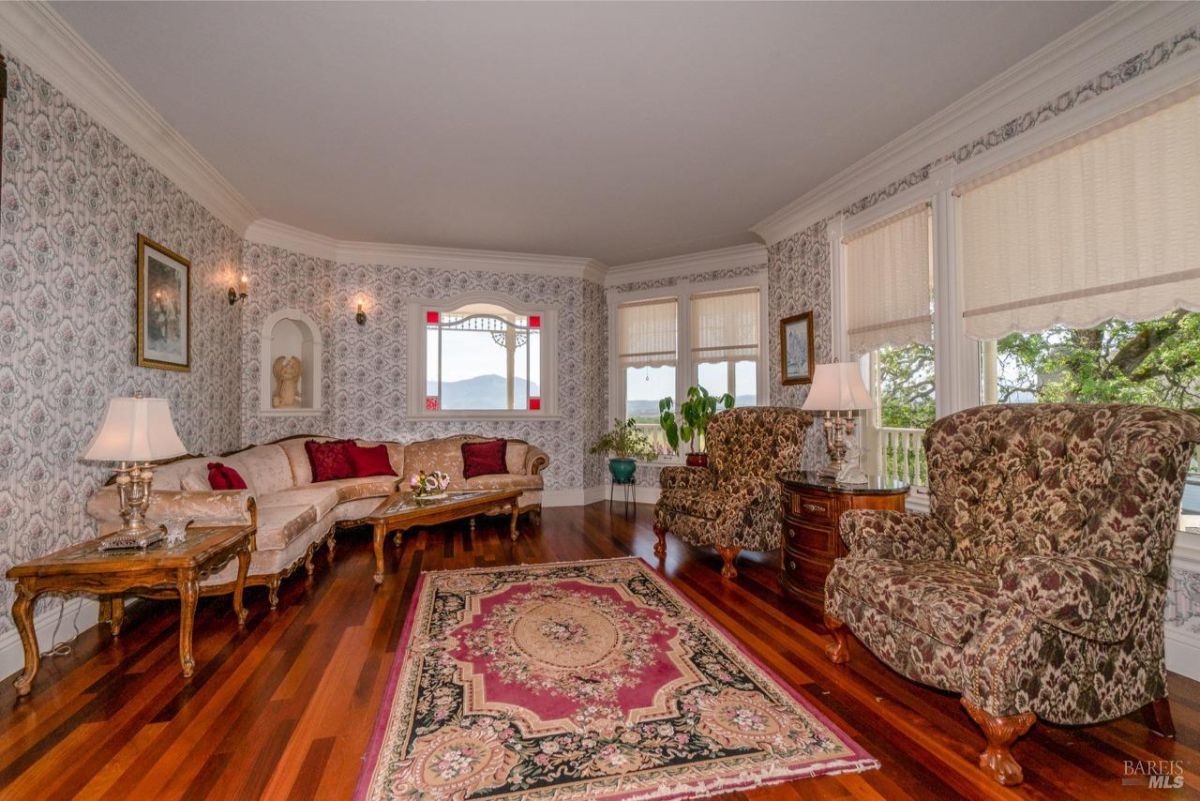 Luxurious living room adorned with patterned wallpaper, classic furniture, and a large bay window.