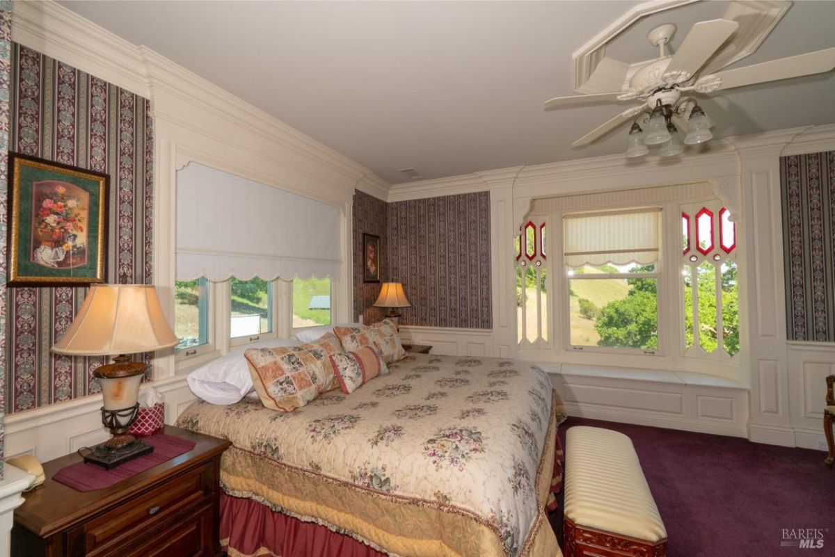 Elegant bedroom with floral-patterned bedding, ornate trim, and a serene view outside.