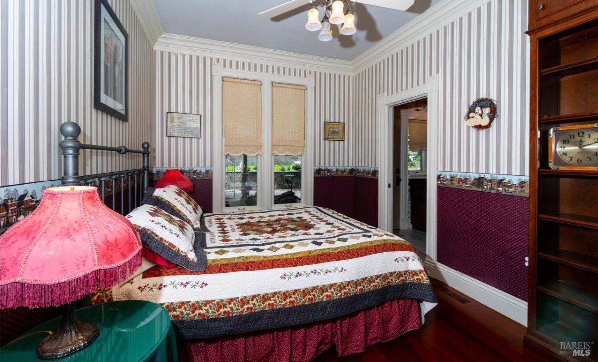 Cozy bedroom with striped wallpaper, a quilted bedspread, and vintage decor.