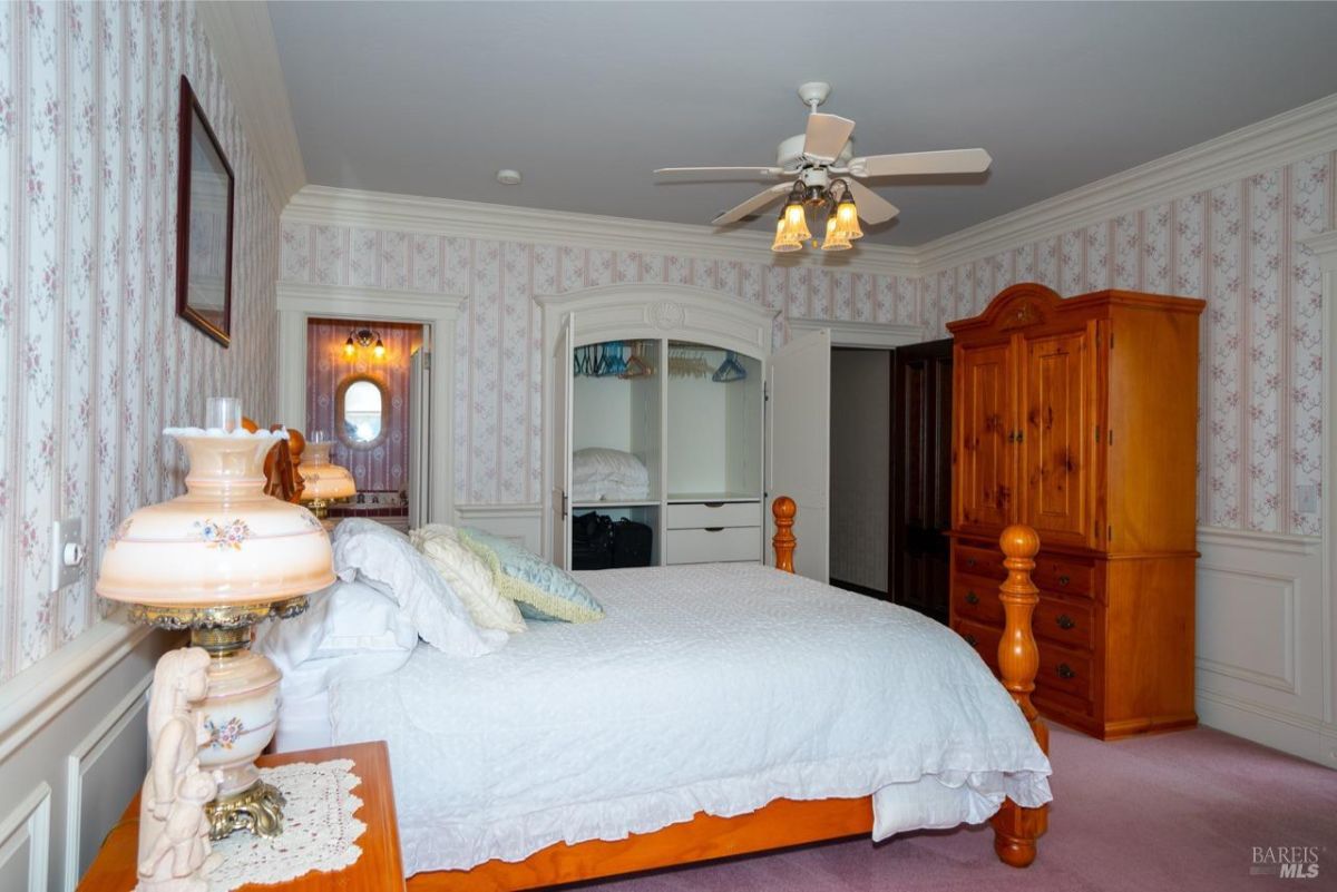 Spacious bedroom featuring a white bed and light floral-patterned wallpaper.