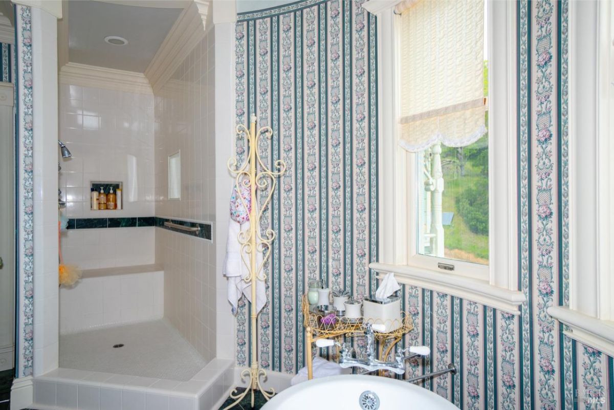 Luxurious shower area with tiled walls and floral-patterned wallpaper.