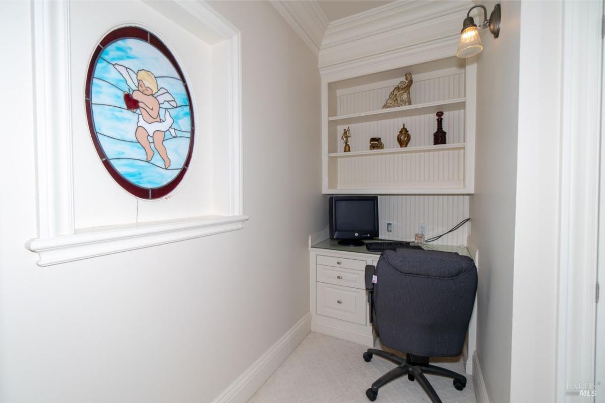 Compact workspace with a stained glass window, built-in shelves, and a desk setup.