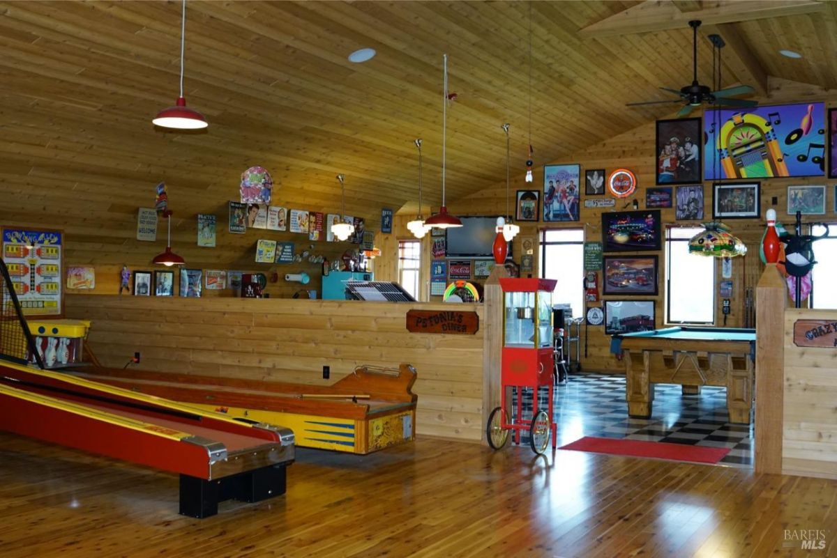 Game room with arcade machines, pinball games, and wooden finishes for a nostalgic ambiance.