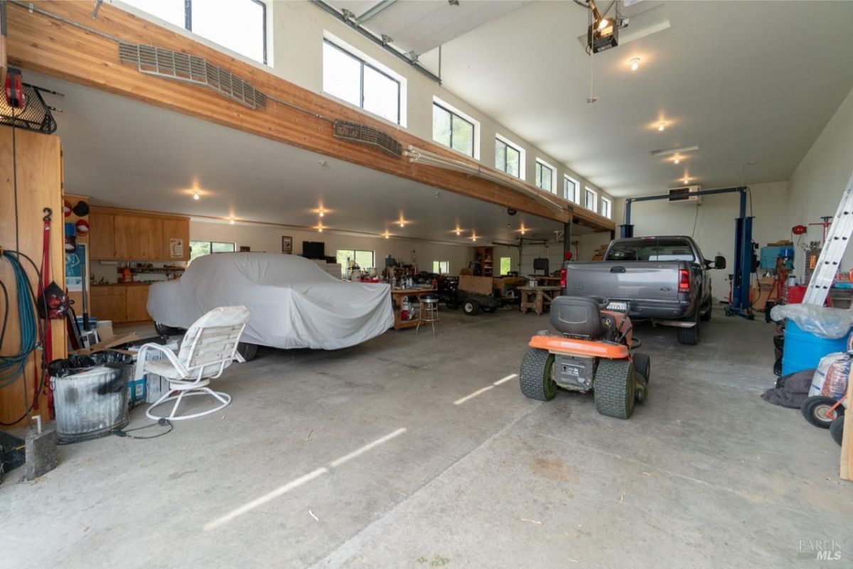 Spacious garage with parked cars, tools, and high ceilings.