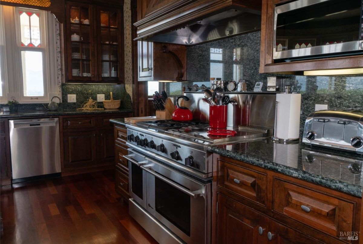 Close-up of a gourmet kitchen featuring stainless steel appliances, wooden cabinetry, and polished granite surfaces.