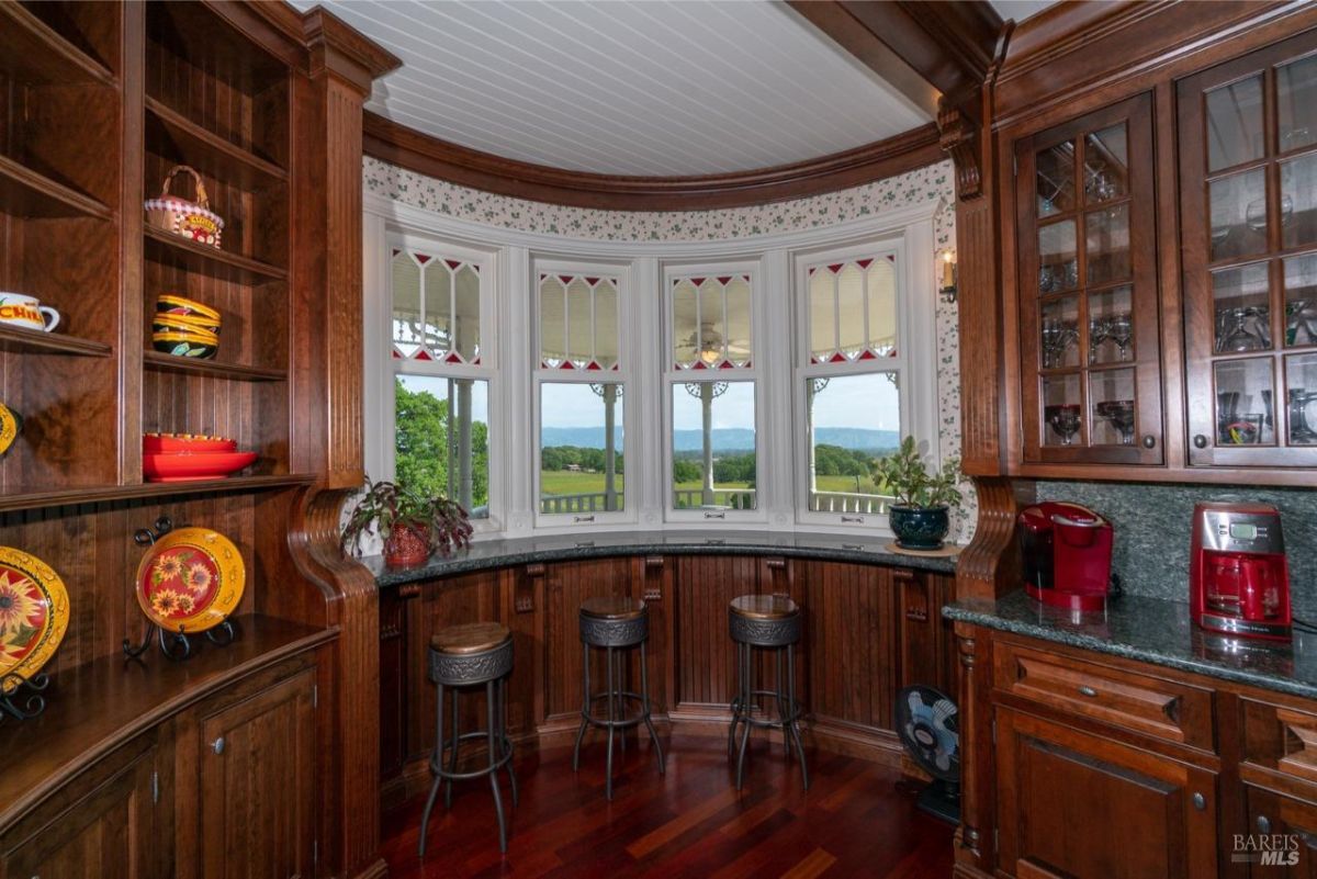 Cozy kitchen nook with decorative wooden cabinetry and a scenic view through stained glass windows.