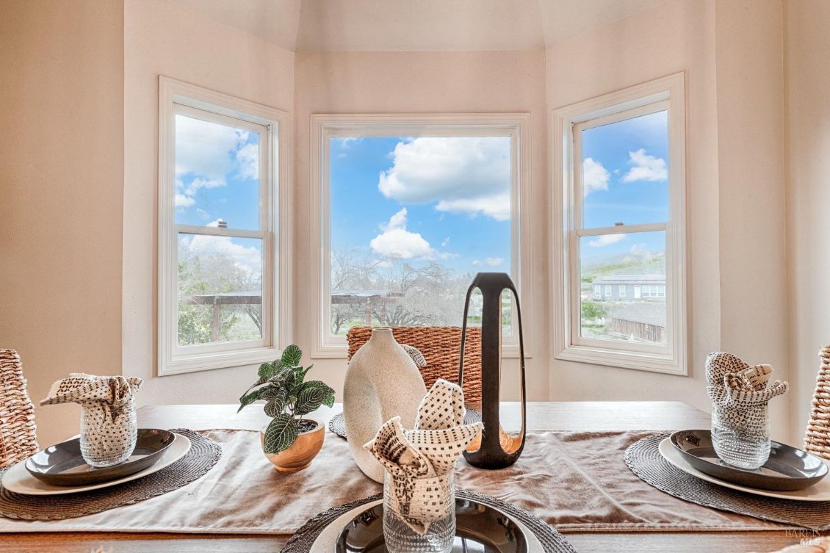 Dining table with plates, napkins, and a view of a landscape.