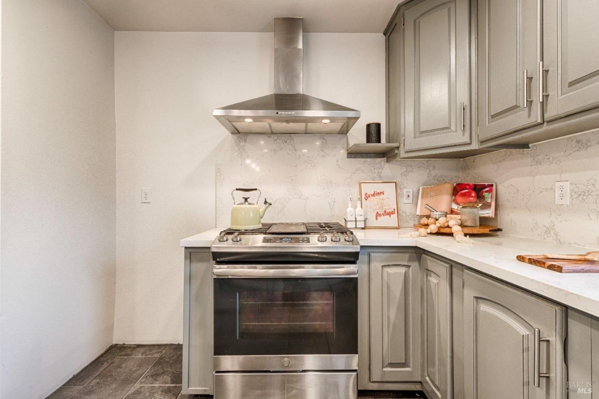 Stainless steel stove and oven with a range hood above.