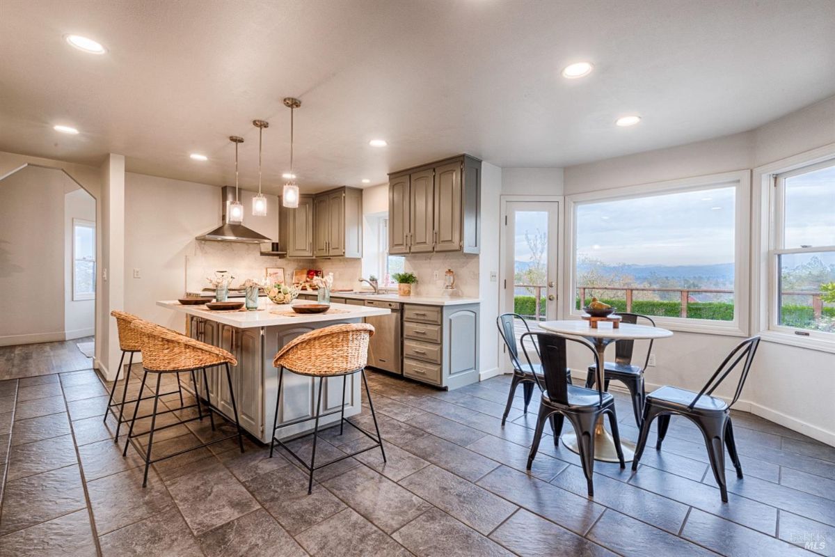 Kitchen with an island, cabinets, a dining table, and a view of a landscape.