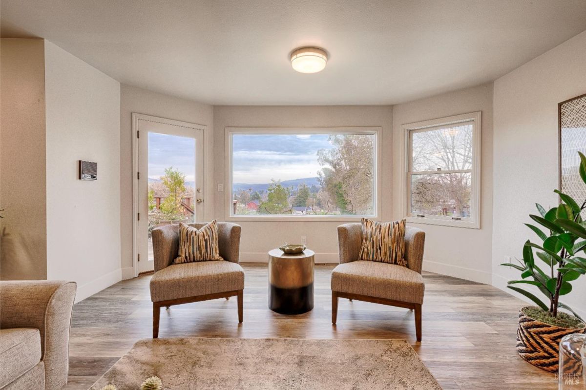 Two armchairs, a coffee table, a plant, and a large window with a view.