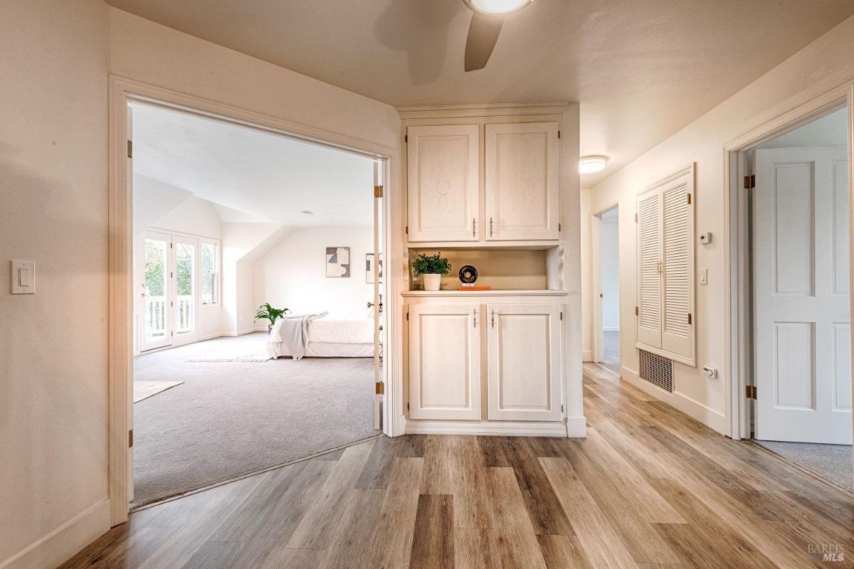 Wood flooring, a built-in cabinet, and a view of a bedroom with French doors.