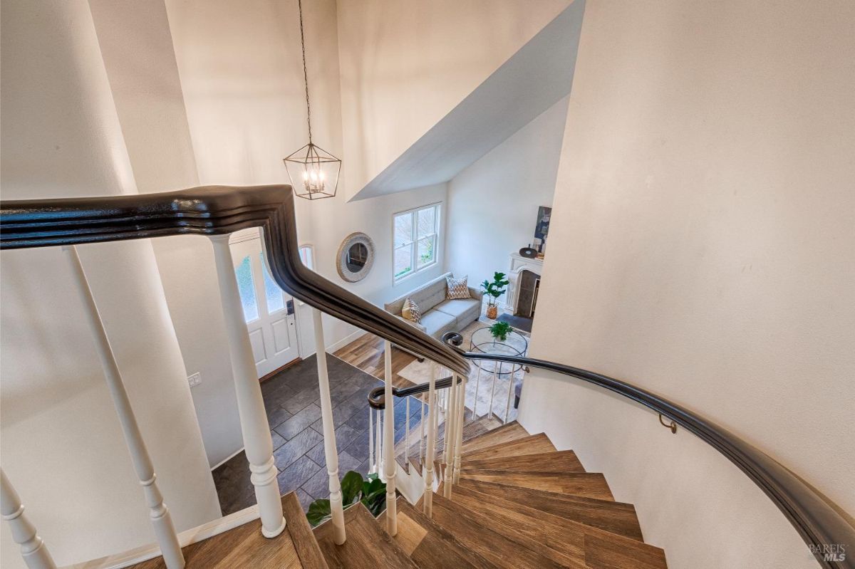 Wooden staircase with a black railing and a view of the living room below.