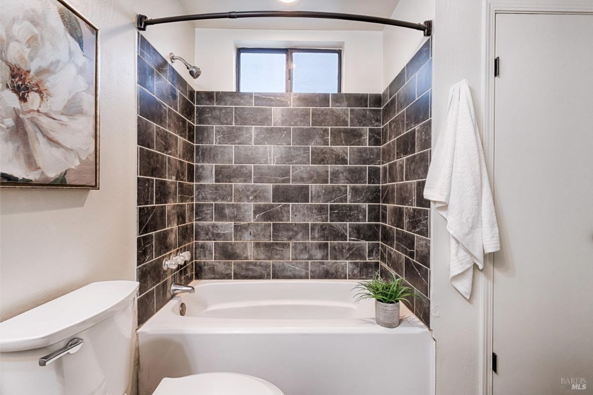 White bathtub, toilet, and a shower with a curved shower rod.