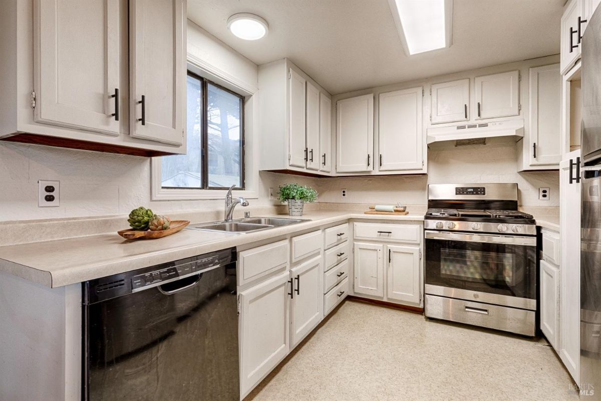 White cabinets, a sink, a stove, a refrigerator, and a dishwasher.