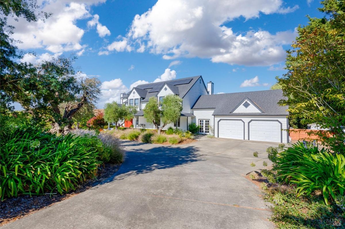 White two-story house with a red front door, a driveway, and a two-car garage.