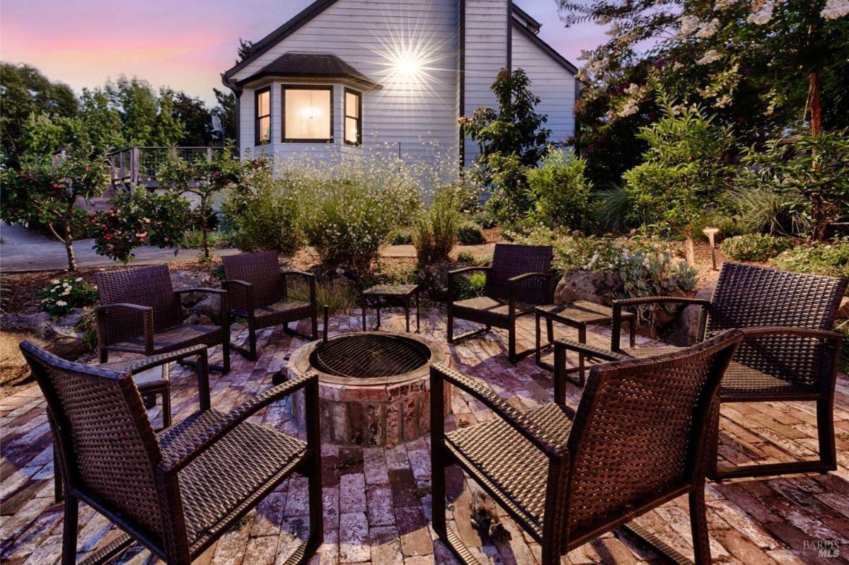 Firepit surrounded by chairs in a backyard at dusk.