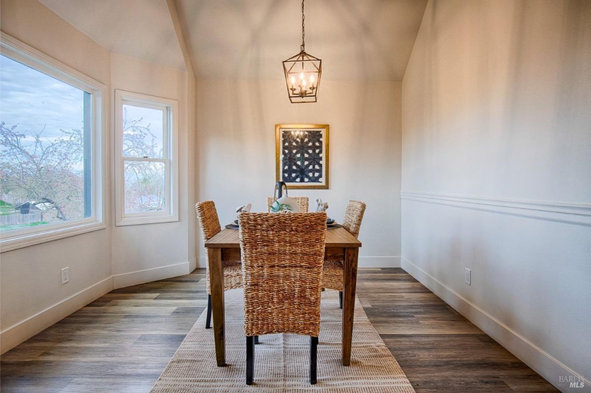 Dining table with four chairs, a large window with a view, and a hanging light fixture.