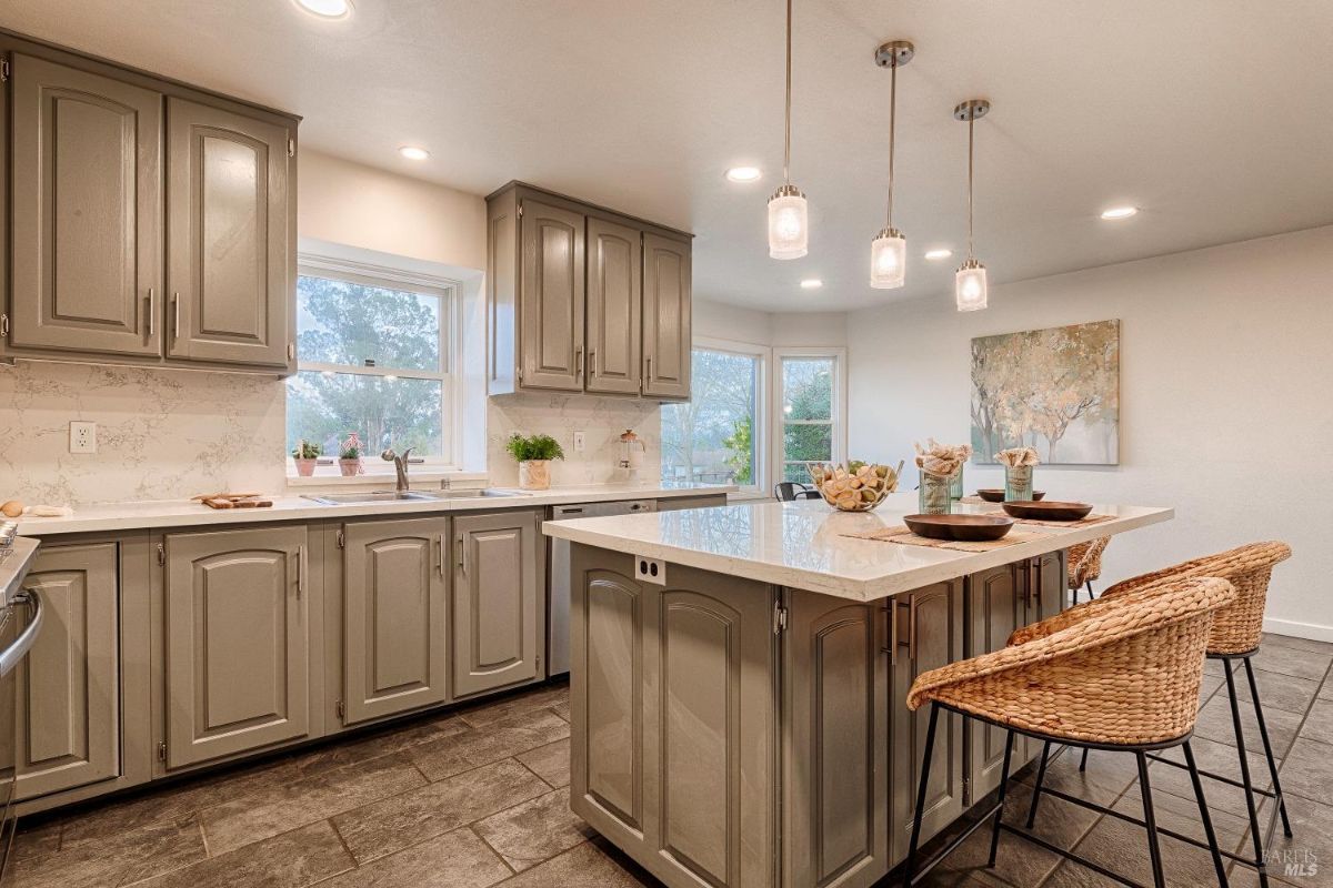 Kitchen with cabinets, a sink, an island, and three hanging lights.