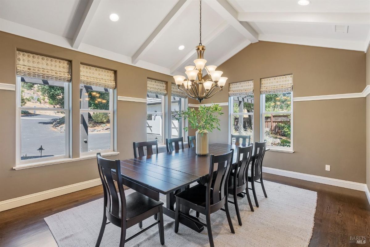 Formal dining room includes vaulted ceilings, a large table, and multiple windows for ample lighting.