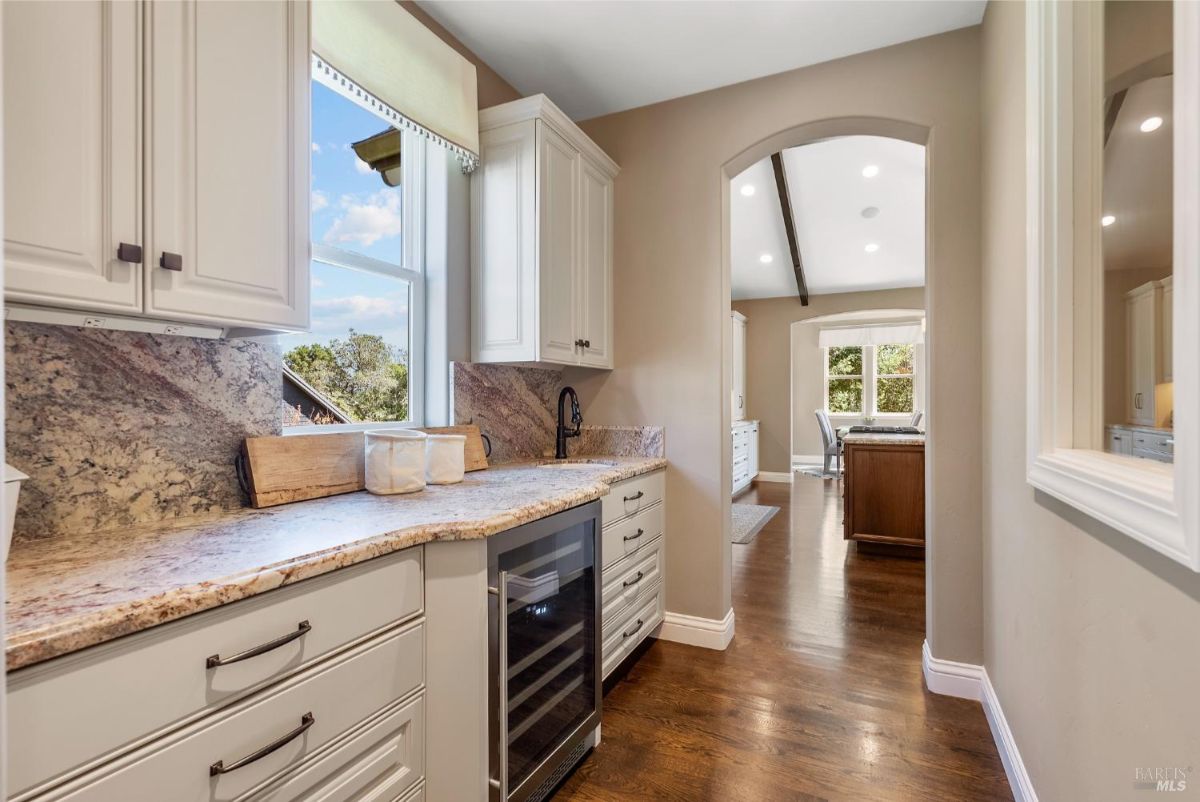 Sleek kitchenette with granite countertops and a view of the outdoors through a sunlit window.