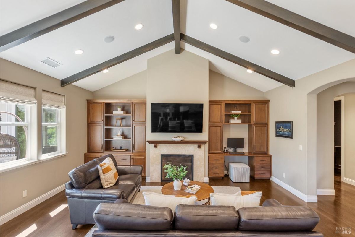 Living room with leather sofas, a built-in fireplace, and wooden cabinetry on either side.