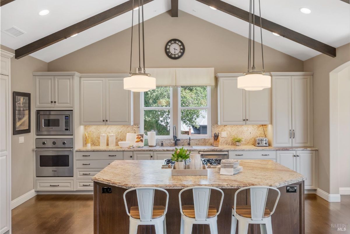 Island-centered kitchen design includes modern appliances, granite countertops, and a cozy breakfast nook.