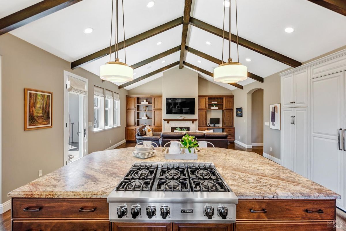 Spacious kitchen island with a Viking stove overlooking a cozy living area with vaulted ceilings.