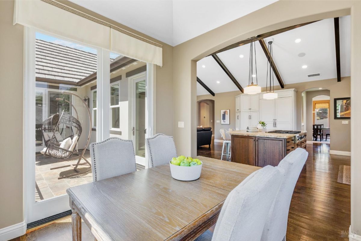 Dining area overlooks a patio with a hanging chair and connects to an open-concept kitchen and living space.