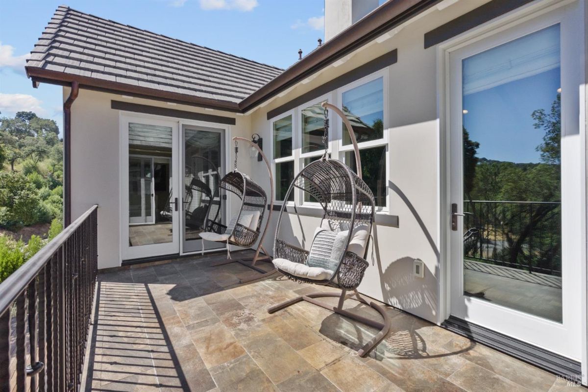 The balcony features two hanging chairs and a view of the surrounding area.