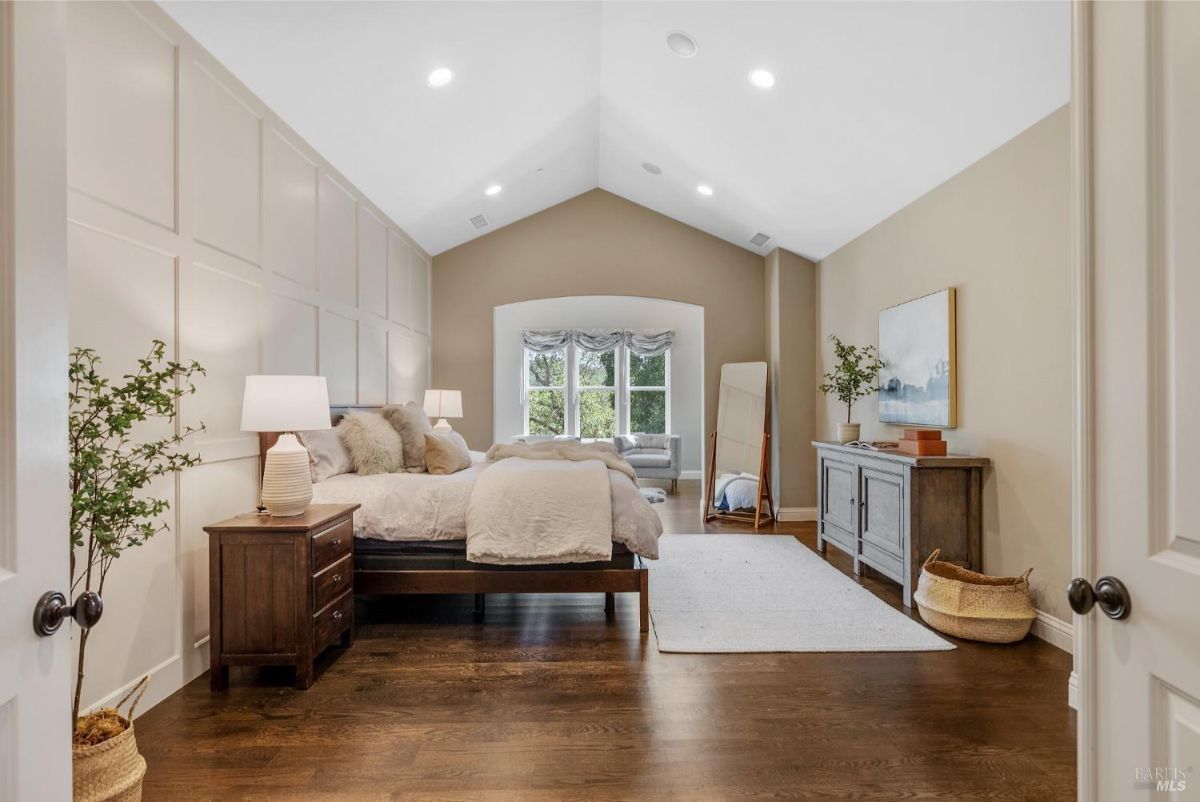 The bedroom features a king-sized bed, two nightstands, a dresser, and a vaulted ceiling.